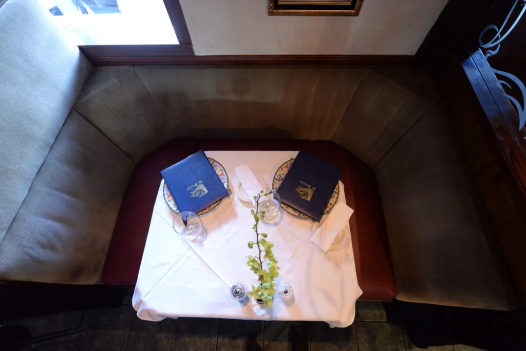 Overhead view of a table set with two blue prayer books, wine glasses, and a floral arrangement with ivy and roses